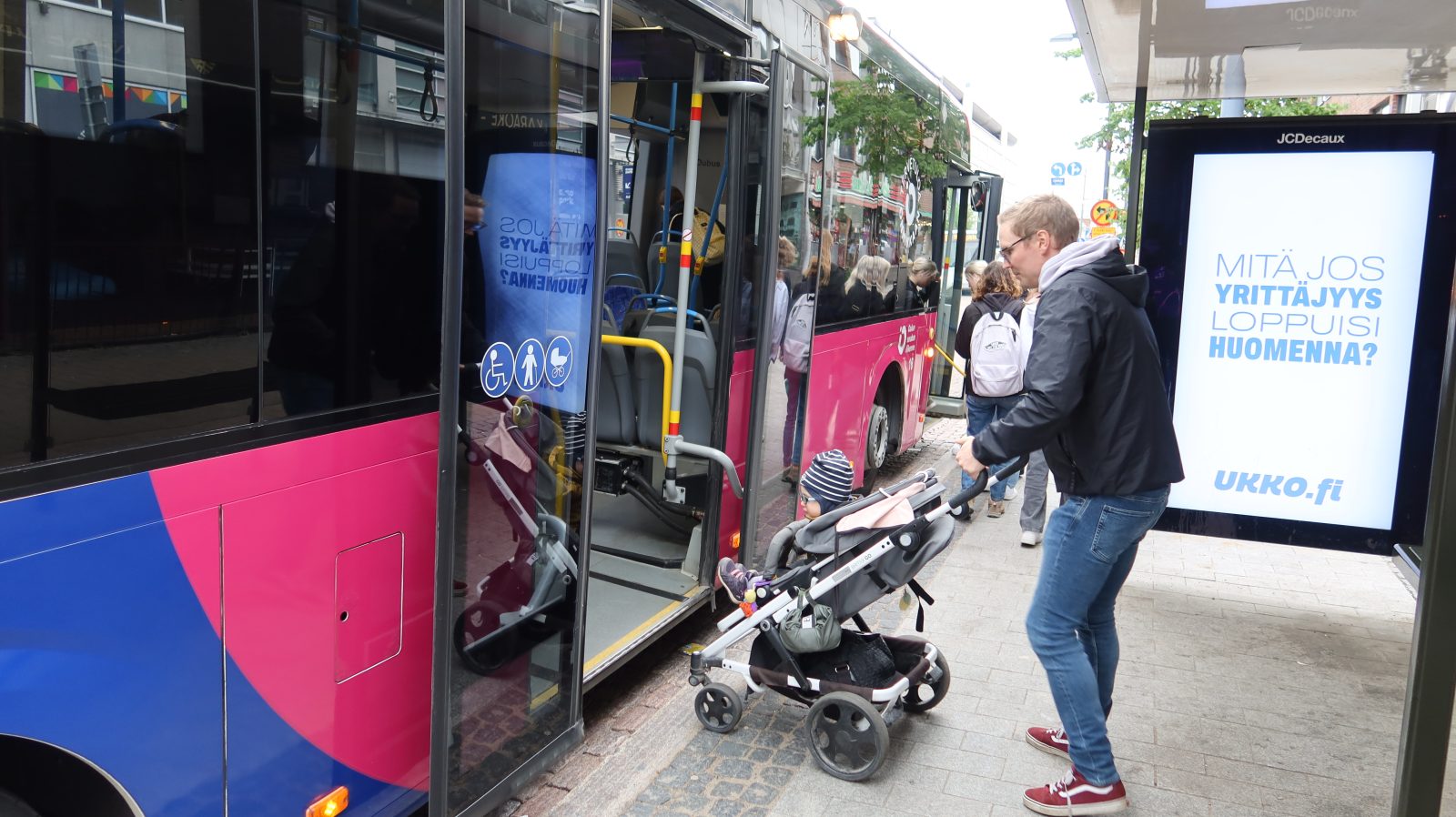 Man getting on bus with a child sitting in a stroller